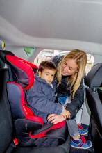 Ein Kind wird in einem Taxi oder Mietwagen mit einer Rückhaltevorrichtung gesichert.